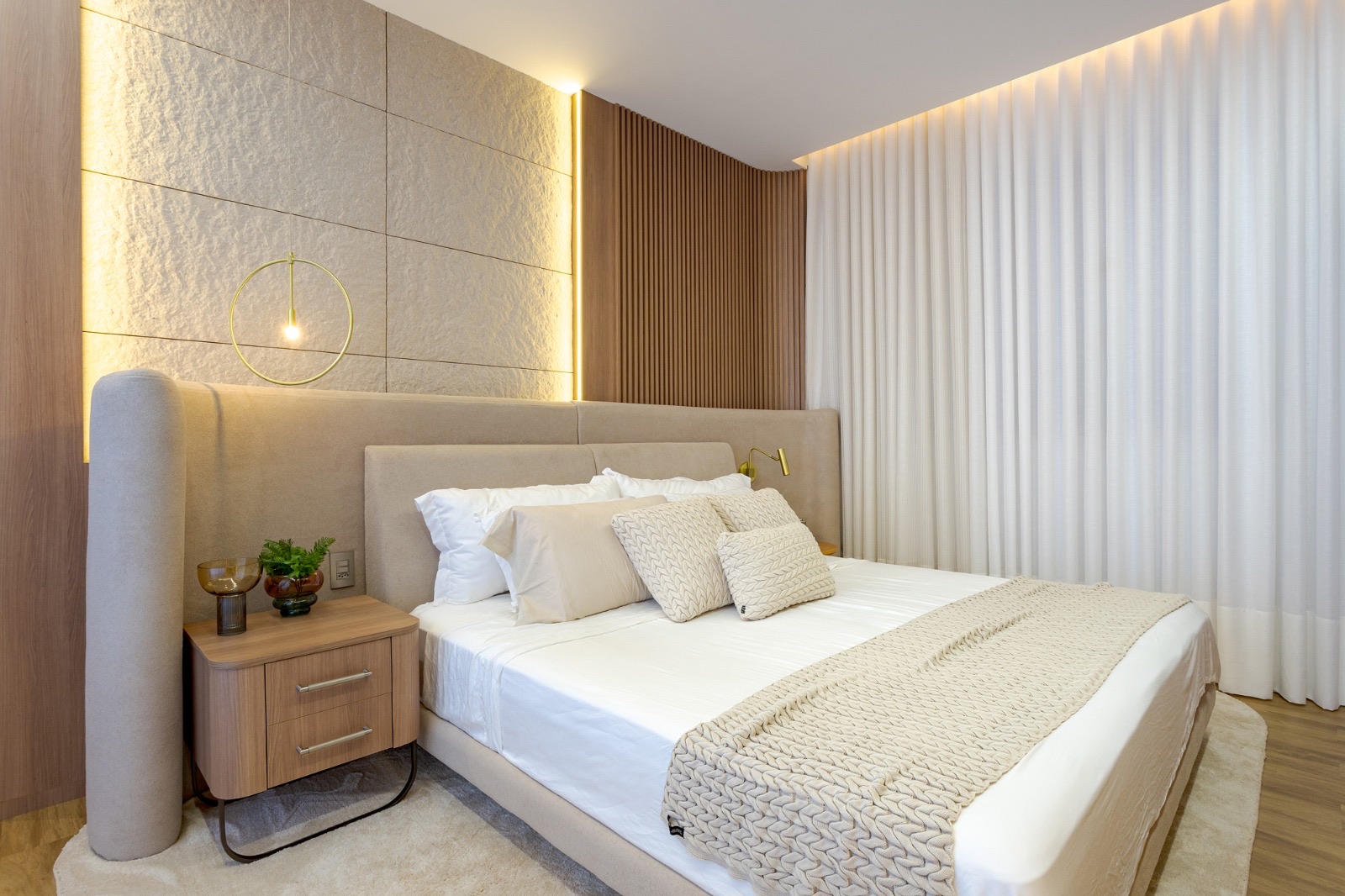 Quarto com cabeceira estofada, cortina de linho e parede texturizada iluminada