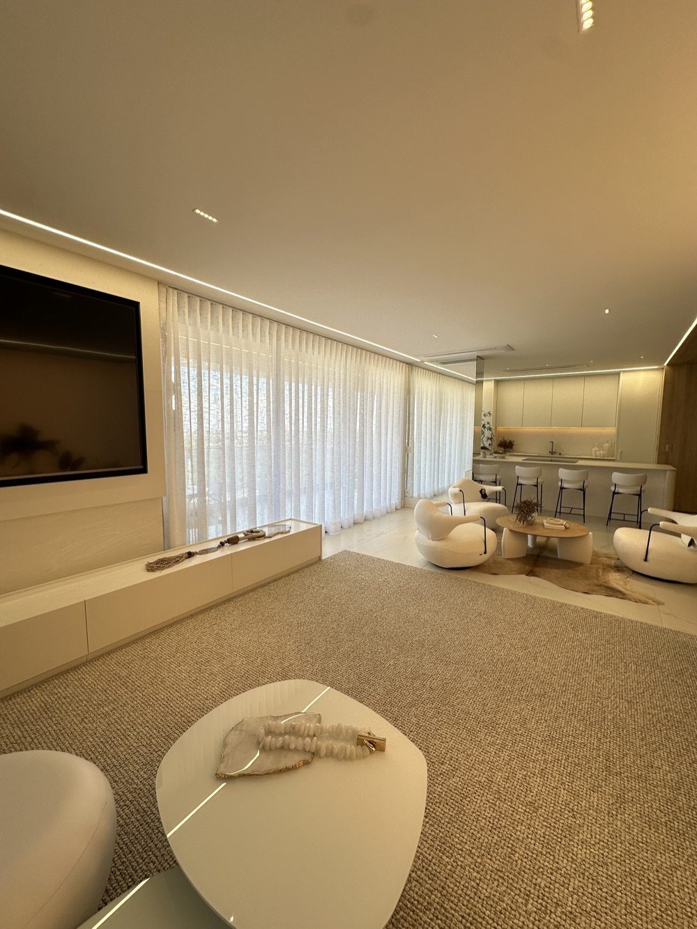 Sala com tapete de fibra natural, poltronas e cortina ao fundo